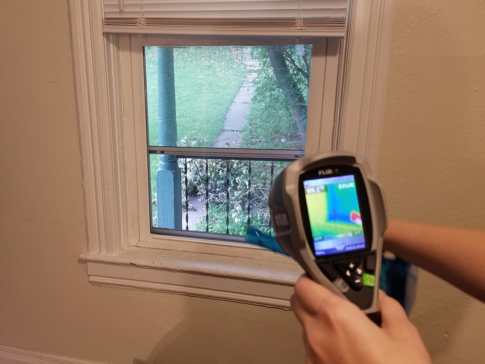 Auditor uses infrared camera to detect air leaks around window.