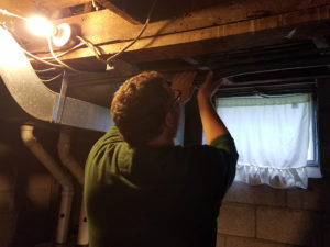Energy auditor puts insulation around pipes in basement