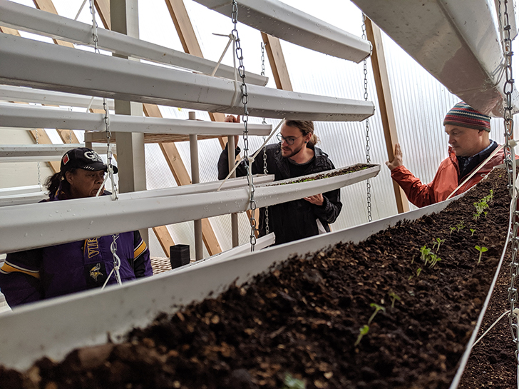 Community members tour the Deep Winter Greenhouse at the Denfeld Food Forest.