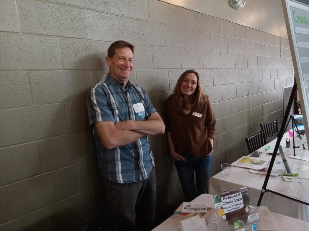 GetGreen representatives, a man and a woman, smile from behind their table at EcoFest.