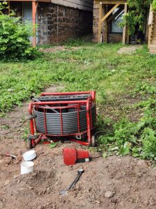 Outside view of Legacy House backyard, showing tubing and tools used for sewer installation.