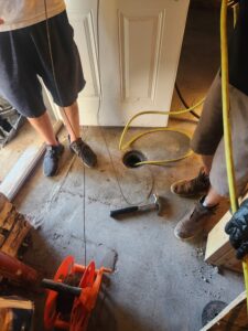 View of sewer opening inside basement of Legacy house, a small nondescript pipe in a concrete floor.