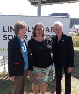 Sen. Smith, Jodi Slick, and Secretary Granholm pose in front of the Lincoln Park Solar Garden sign.