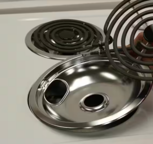 Close up of metal pan, the part that sits under the electric coil, being replaced on electric stovetop.