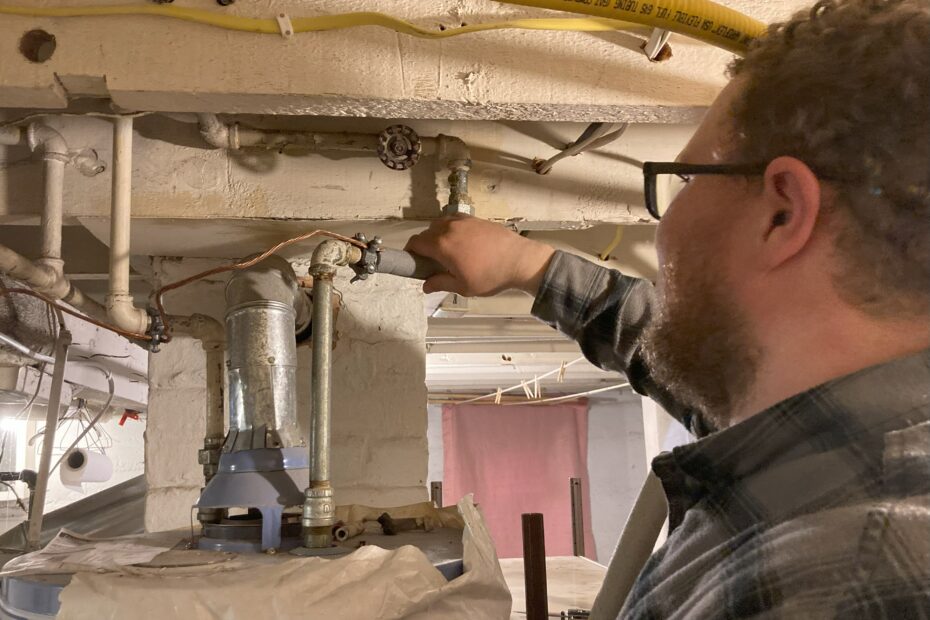 Energy auditor insulates a pipe leading into a hot water heater.