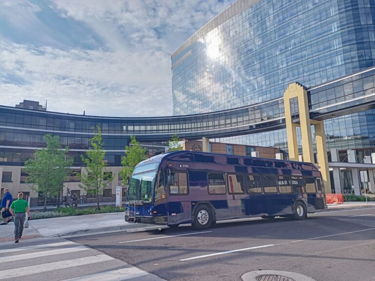 New blue DTA bus parked in front of the Essentia building.