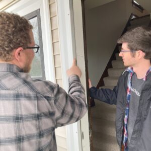 Two people examine a doorjamb.