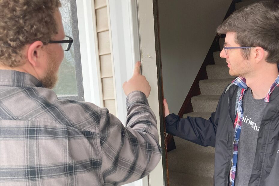 Two people examine a doorjamb.