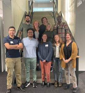 Ten people stand in a staircase smiling at the camera.