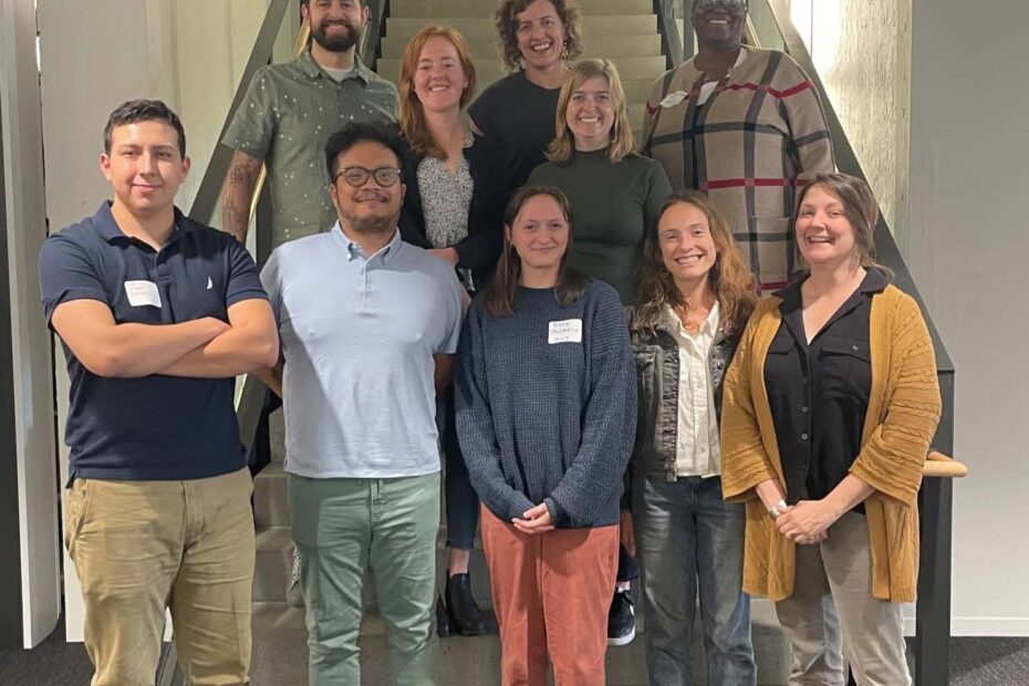 Ten people stand in a staircase smiling at the camera.