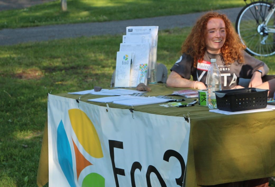 smiling person sit at outdoor table with Eco3 logo on the front
