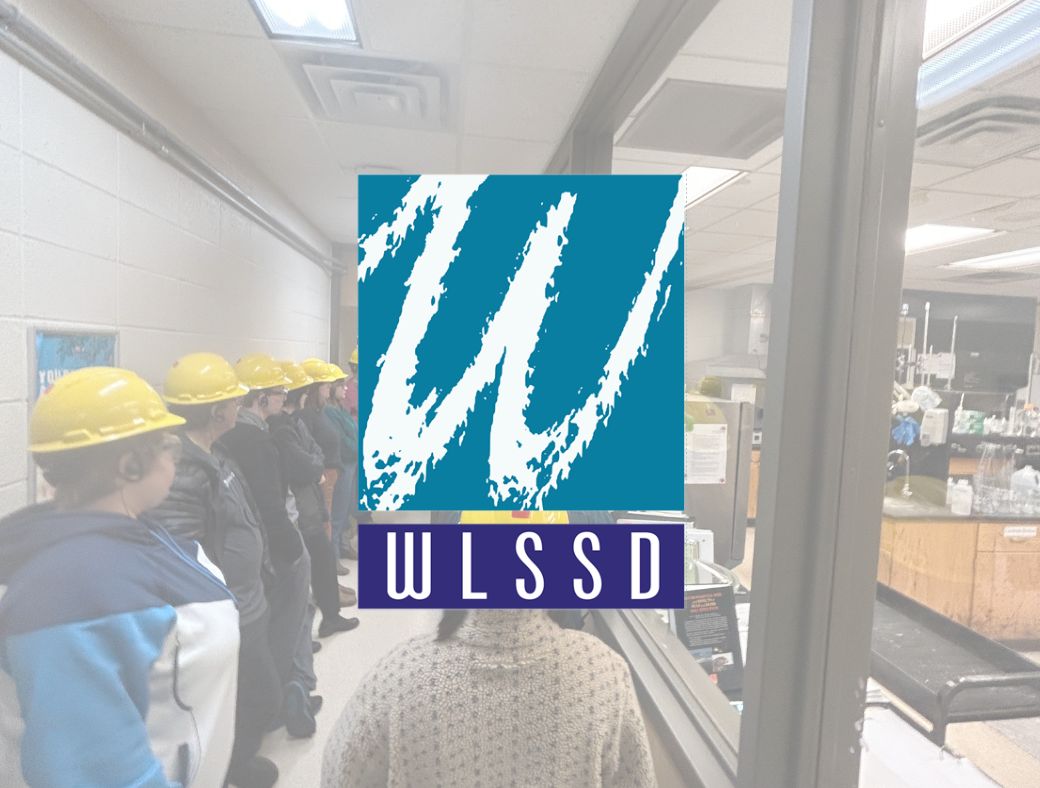 WLSSD logo over faded image of people in hard hats lined up in a hallway
