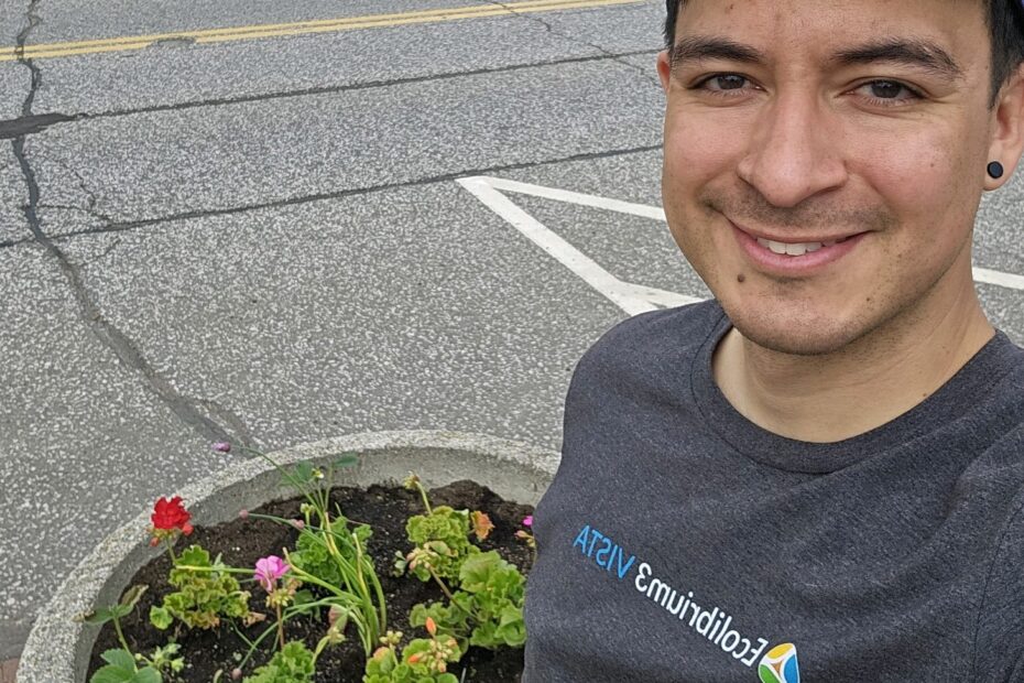 Smiling person poses by planter