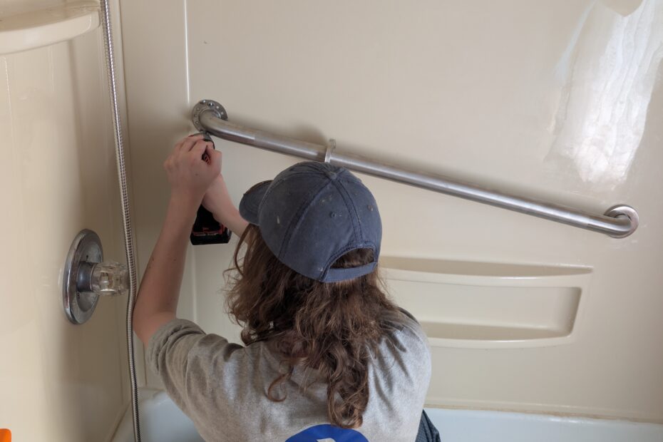 Person installing grab bar in bath tub.