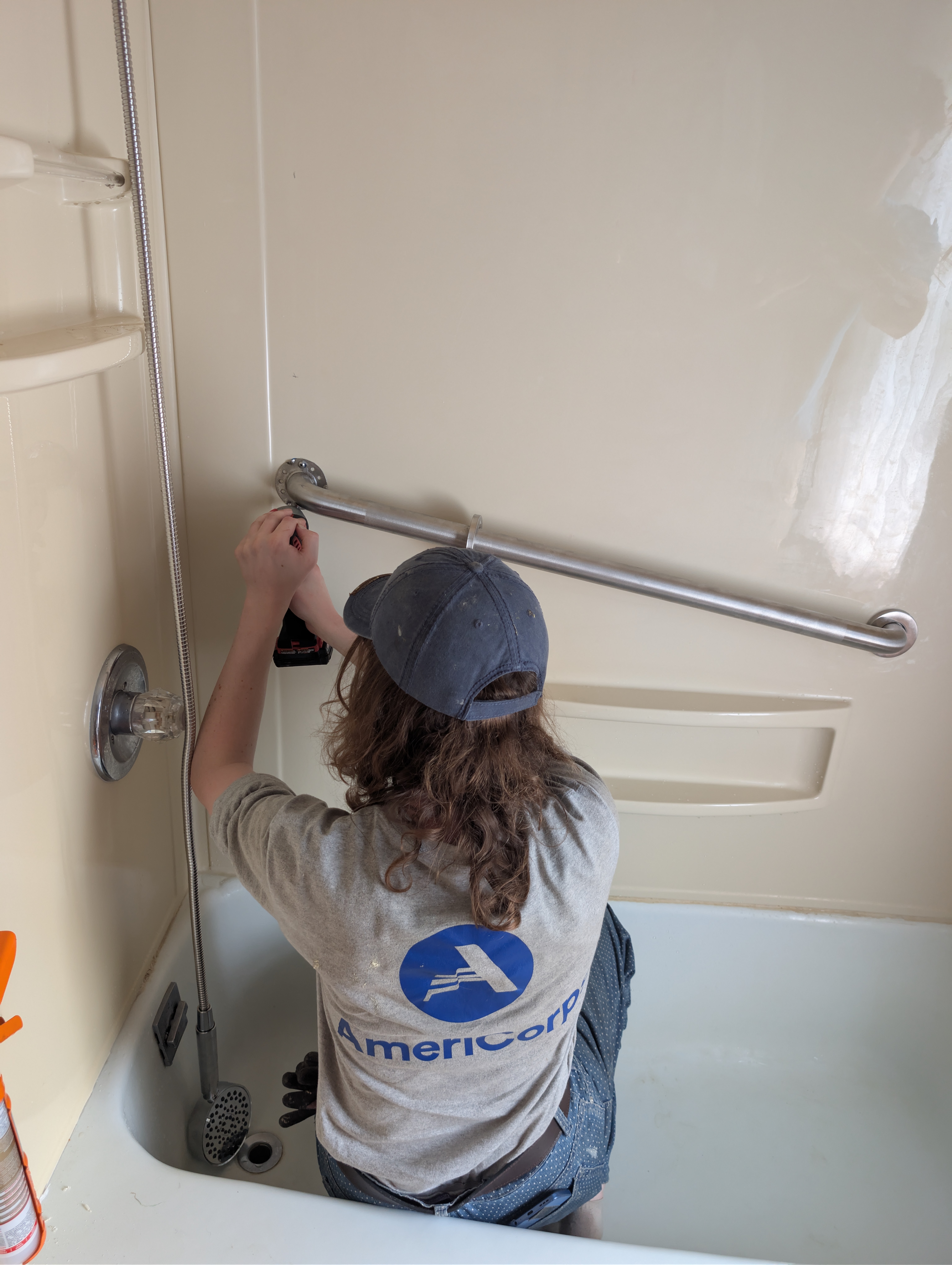 Person installing grab bar in bath tub.