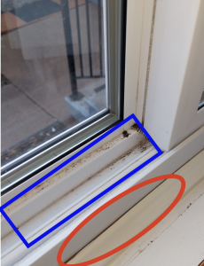 Close up view of a windowsill. The window is the type that opens by sliding the panes left or right. There is a blue box around the space where the window would slide open. A red circle highlights a small gap between the windowpane and the window sill.